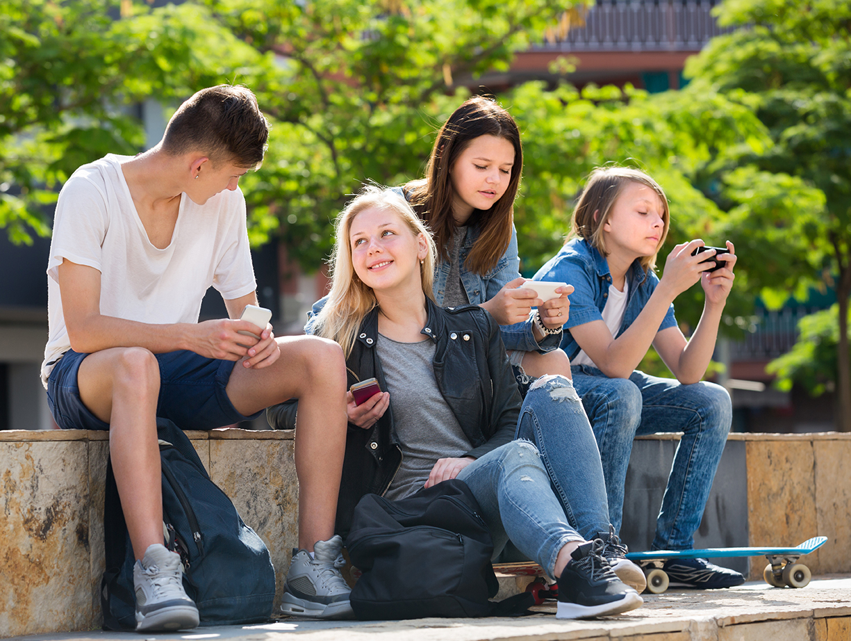 Happy girls and boys playing with mobile phones